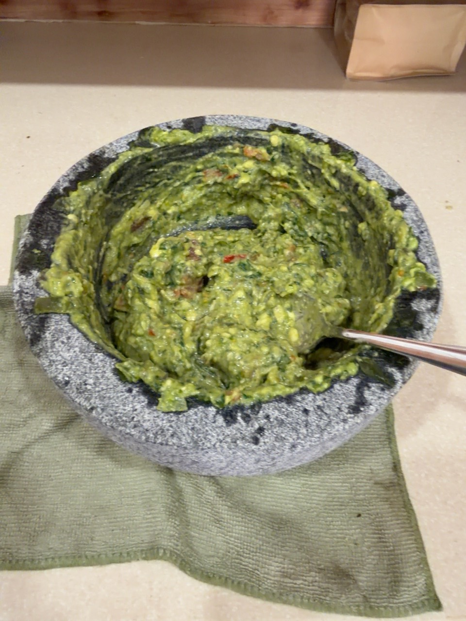 Finished guacamole with a spoon in the molcajete.